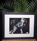 Framed action photograph of two football players in a game, signed by a player, with a black frame.